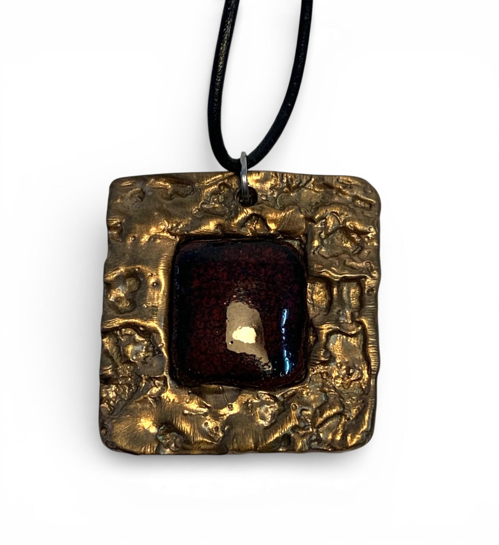 Bronze pendant with texturized surface and agate stone insert and leather chain.