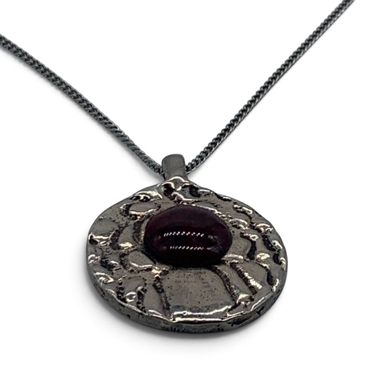 Close-up of the textured bronze and the round garnet enamel cabochon