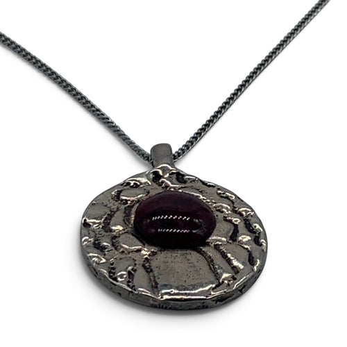 Close-up of the textured bronze and the round garnet enamel cabochon